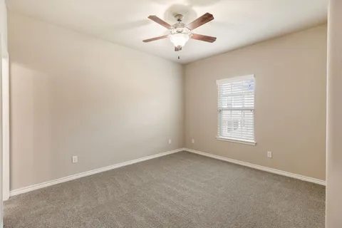 an empty room with a window and a ceiling fan