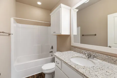 a bathroom with a granite countertop sink a toilet and shower
