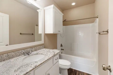 a bathroom with a granite countertop sink a toilet and shower