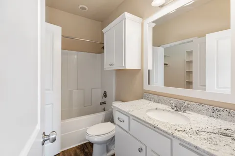 a bathroom with a granite countertop sink toilet and shower