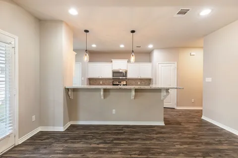 a view of a kitchen with cabinets and wooden floor