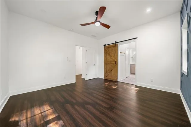 a view of an empty room with wooden floor and a ceiling fan