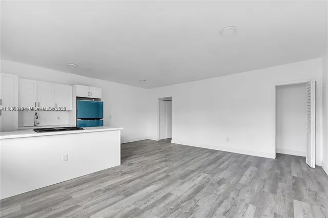a kitchen with wooden floor and white stainless steel appliances
