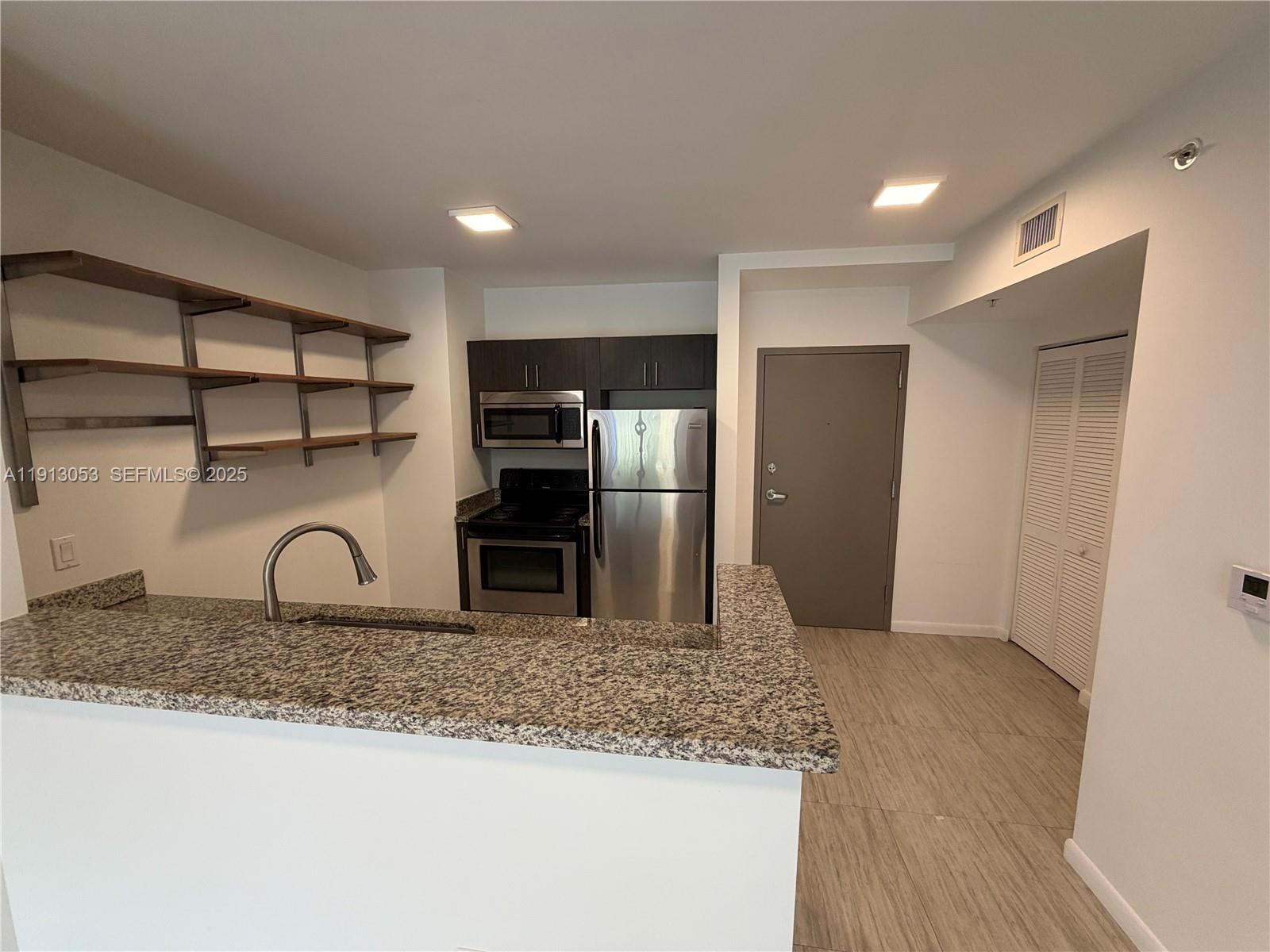 1801 Southwest 32nd Avenue, Unit 504 Miami, FL 33145 - Photo 8 of 14 a kitchen with granite countertop a refrigerator and a sink