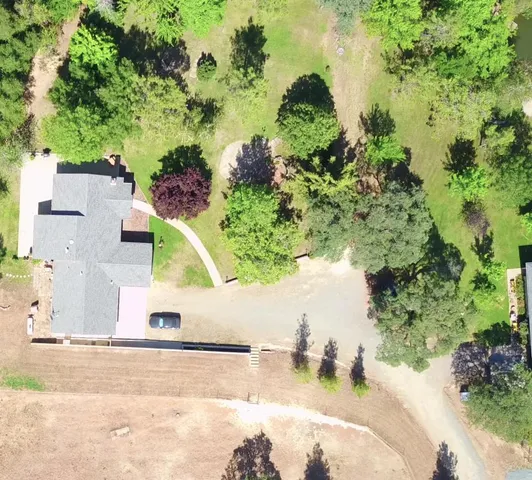 an aerial view of residential house with outdoor space and trees all around