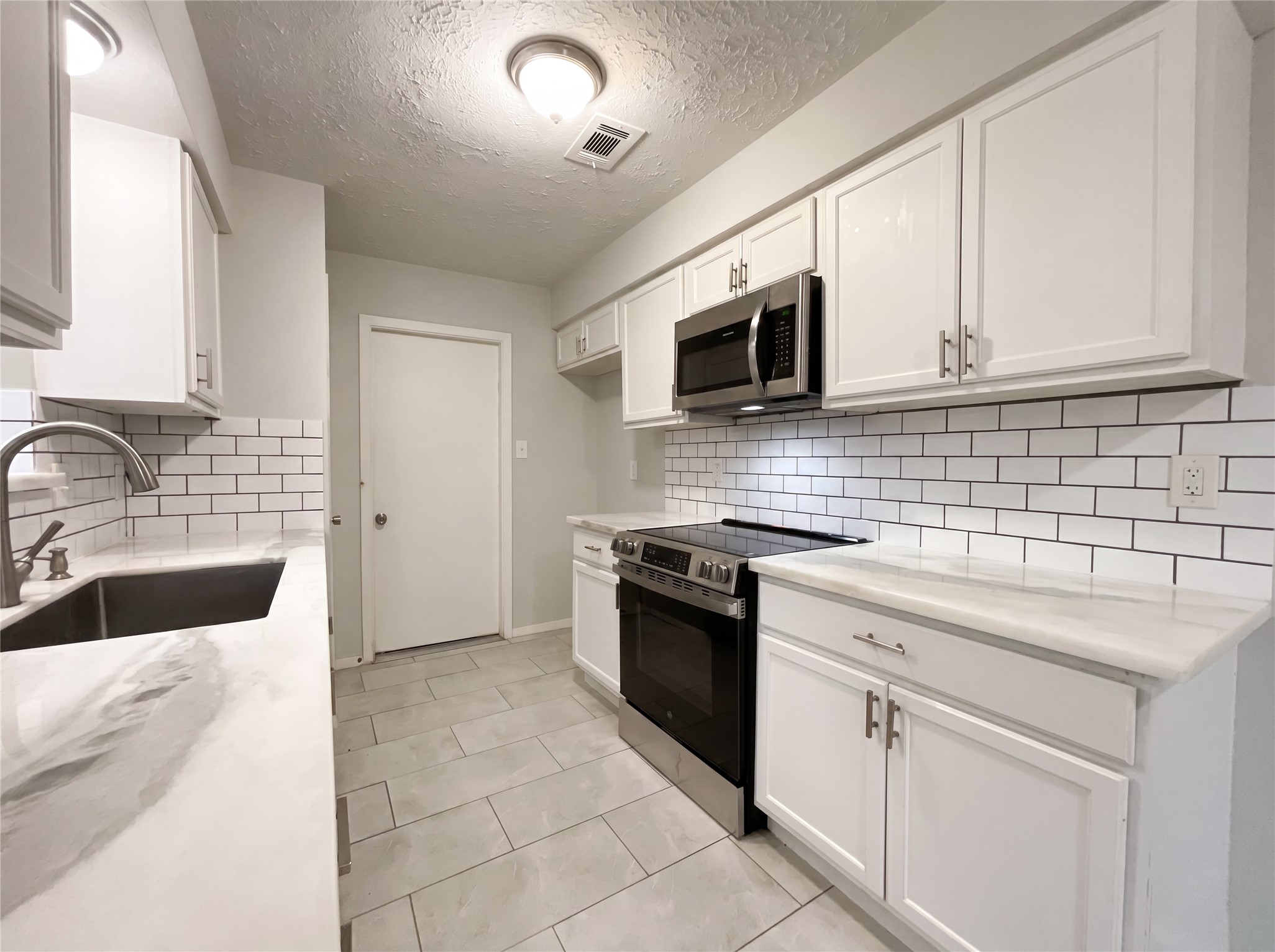 23110 Pennsgrove Road Spring, TX 77373 - Photo 2 of 16 a kitchen with granite countertop a sink dishwasher stove and microwave with wooden cabinets