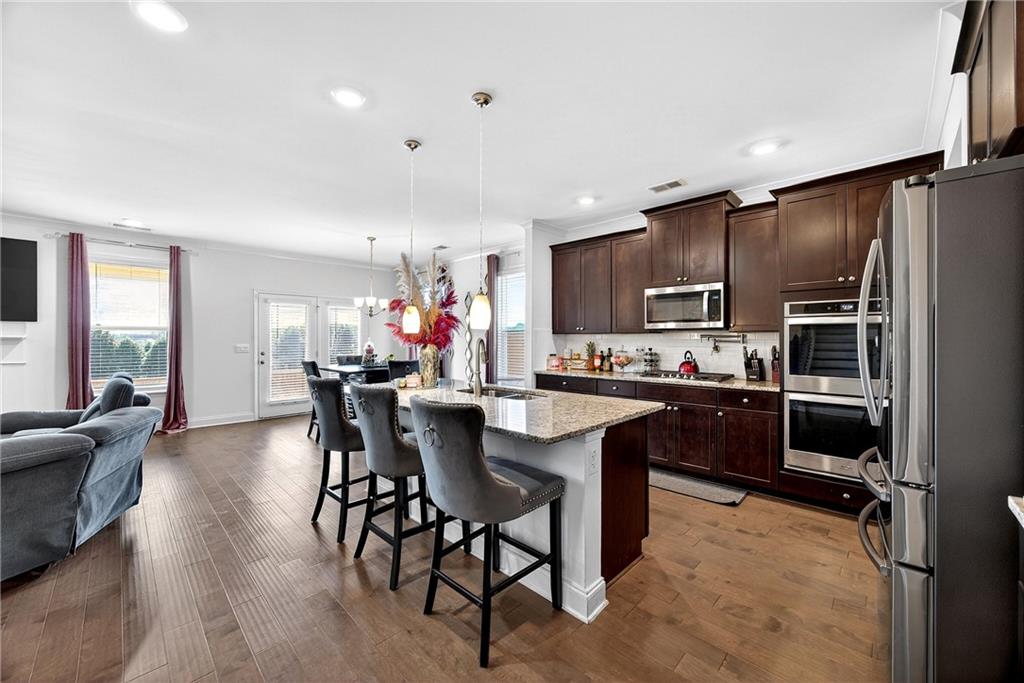 419 Beachview Road Hampton, GA 30228 - Photo 8 of 32 a kitchen with stainless steel appliances kitchen island granite countertop a refrigerator a stove a sink a dining table and chairs with wooden floor