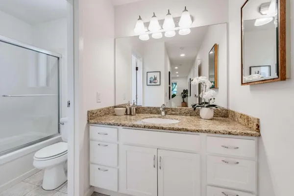 a bathroom with a granite countertop sink a toilet and a mirror