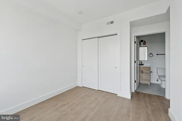 a view of a room with wooden floor a bathroom sink and a bathroom