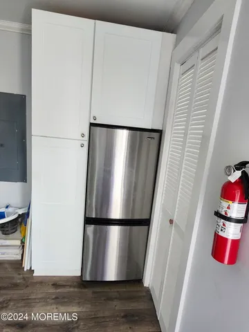 a kitchen with a refrigerator and wooden floor