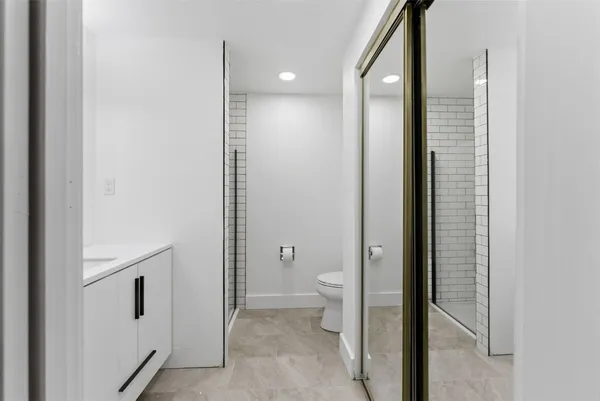 a bathroom with a granite countertop sink a toilet and shower