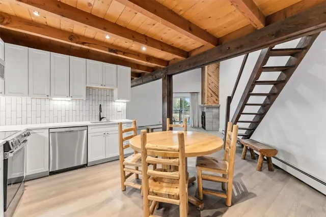 a kitchen with stainless steel appliances a table chairs sink and cabinets