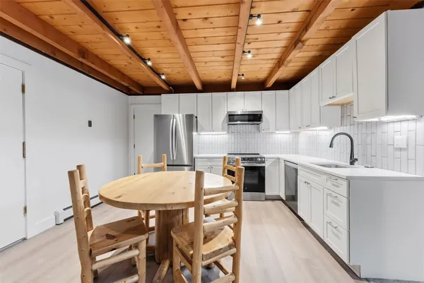 a kitchen with stainless steel appliances a table chairs sink and cabinets