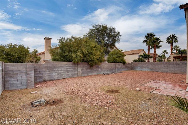 2647 Ridgewater Circle Henderson, NV 89074 - Photo 25 of 26 An enclosed backyard features gravel ground cover, brick paving, and a concrete block privacy wall.