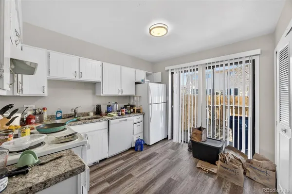 a kitchen with stainless steel appliances granite countertop a refrigerator stove oven and white cabinets with wooden floor
