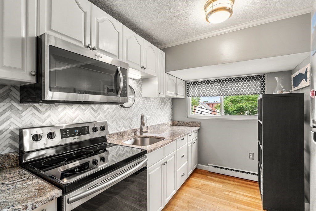 12 Cox Court, Unit 4 Beverly, MA 01915 - Photo 2 of 7 a kitchen with a stove a microwave and cabinets