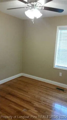 en empty room with wooden floor and fan