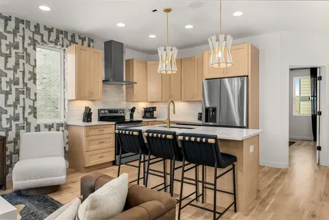 a kitchen with stainless steel appliances granite countertop a stove a refrigerator a kitchen island a dining table and chairs