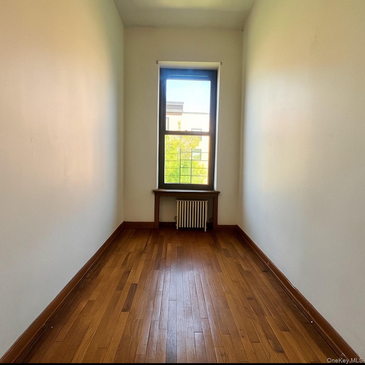 451 West 162nd Street, Unit 3 Manhattan, NY 10032 - Photo 12 of 12 a view of an empty room with wooden floor and a window