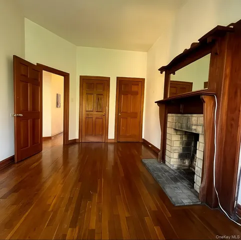 a view of an empty room with wooden floor and a fireplace