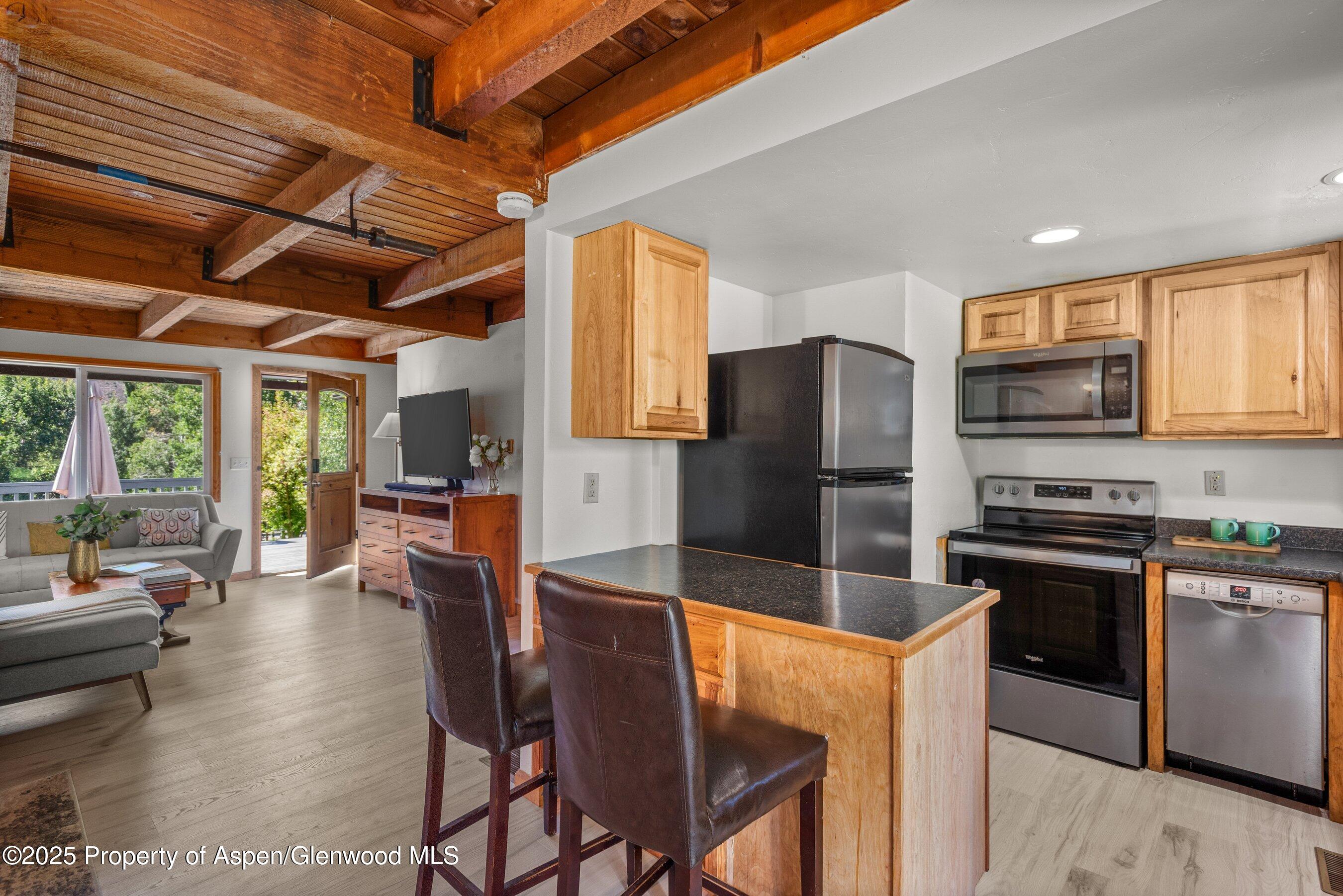 331 Holland Hills Road, Unit 5 Basalt, CO 81621 - Photo 4 of 19 a kitchen with stainless steel appliances granite countertop a stove top oven a sink dishwasher a dining table and chairs with wooden floor