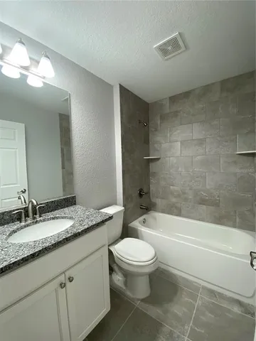 a bathroom with a granite countertop toilet a sink and bathtub
