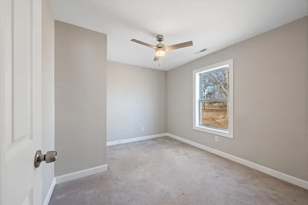 an empty room with windows and fan