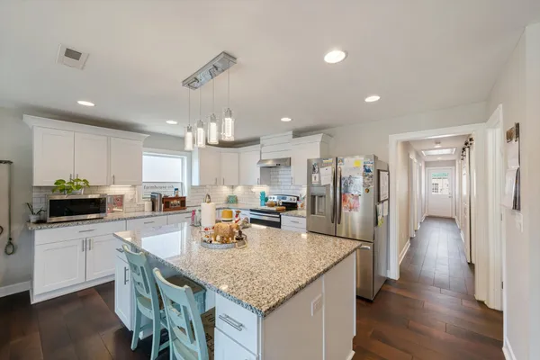a kitchen with stainless steel appliances granite countertop a kitchen island sink refrigerator and cabinets