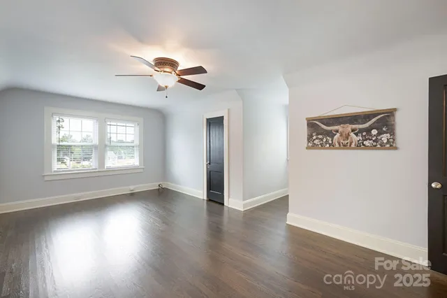 an empty room with wooden floor chandelier fan and windows