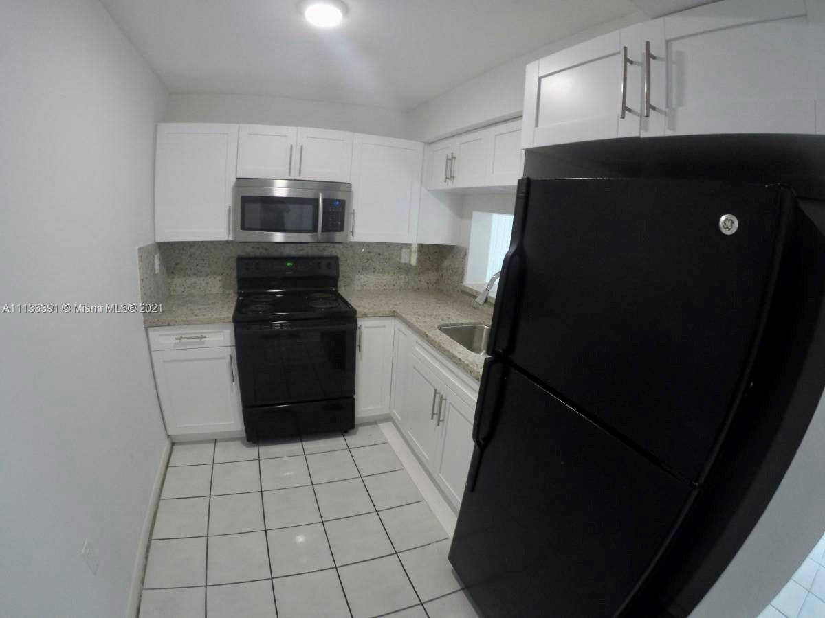 11780 Southwest 18th Street, Unit 2292 Miami, FL 33175 - Photo 2 of 10 a kitchen with a refrigerator a stove top oven and cabinets