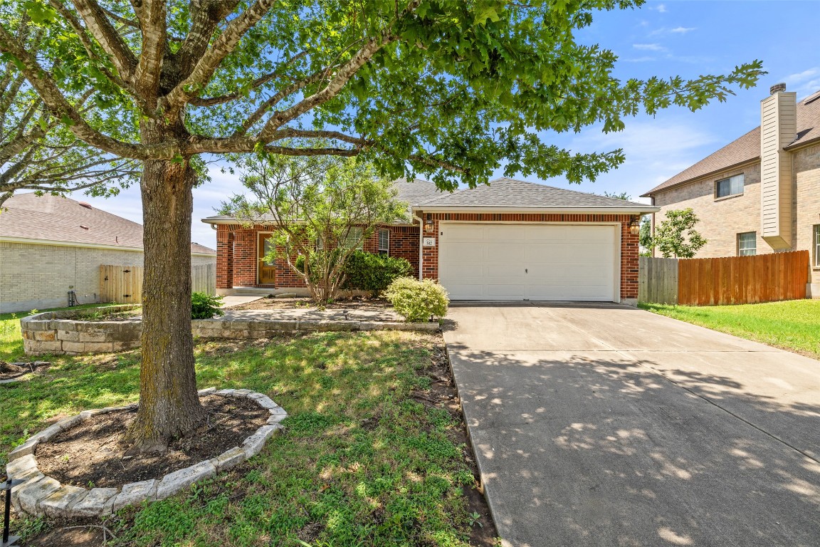 Single story home featuring brick siding, driveway, an attached garage, and a shingled roof