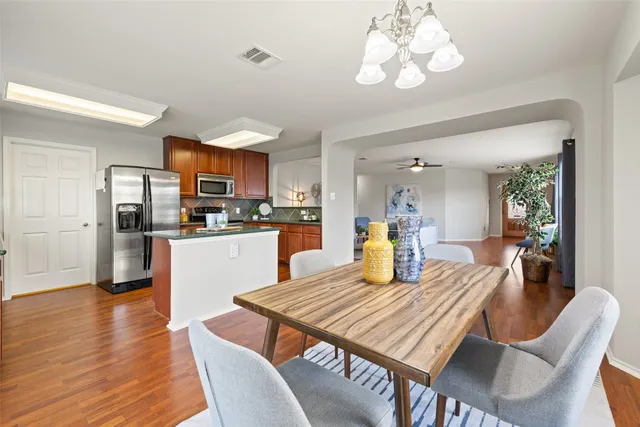 a kitchen with stainless steel appliances granite countertop a dining table chairs stove refrigerator and cabinets