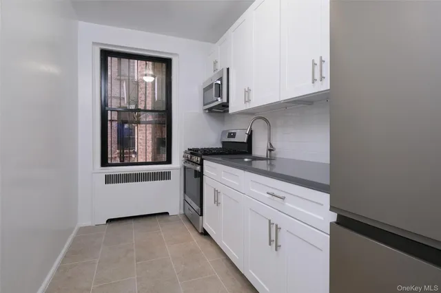 a kitchen with granite countertop white cabinets and stainless steel appliances