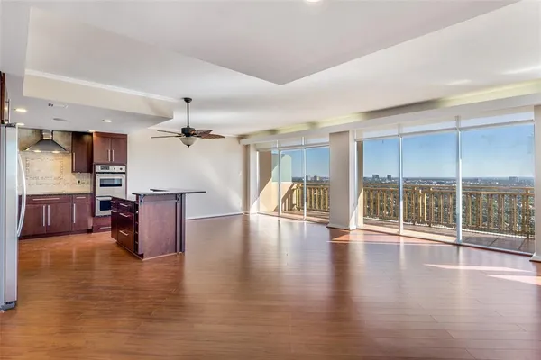 a view of a living room a kitchen with a large window and wooden floor