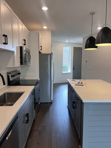 a kitchen with a sink a refrigerator and a stove top oven with wooden floor