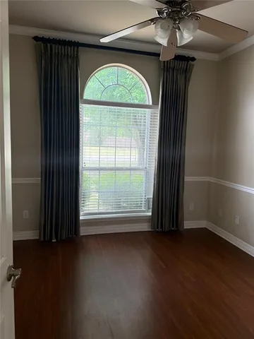 an empty room with wooden floor fan and windows
