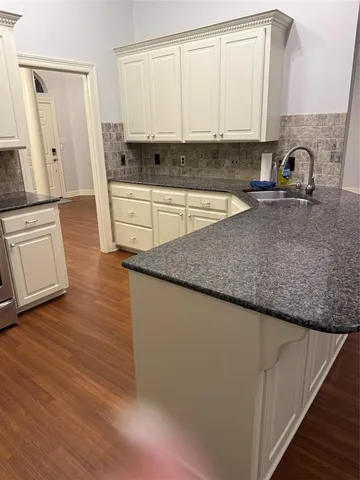 a kitchen with granite countertop a sink a stove and cabinets
