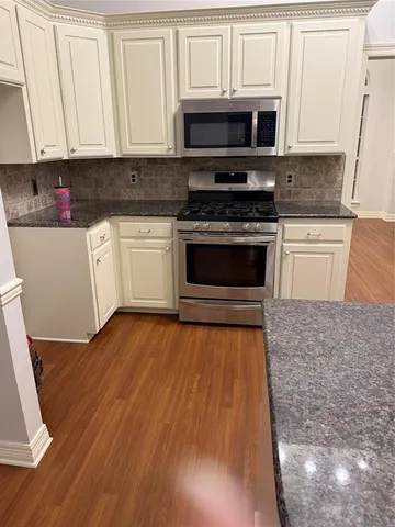 a kitchen with stainless steel appliances granite countertop a stove a sink and a microwave