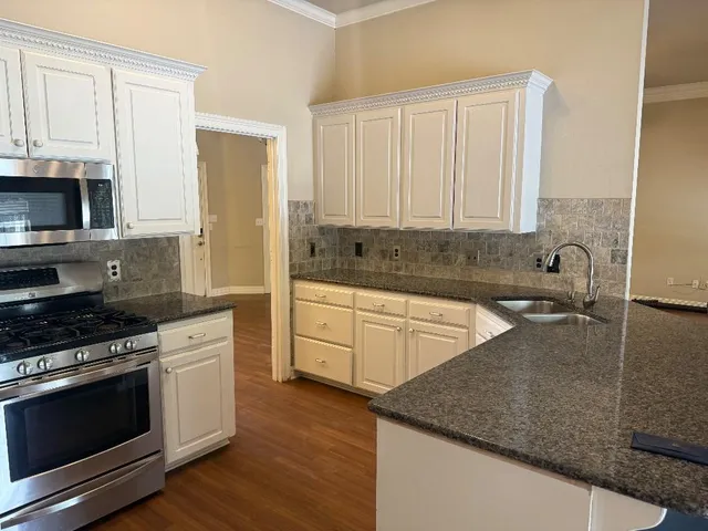 a kitchen with stainless steel appliances granite countertop a stove a sink and a microwave