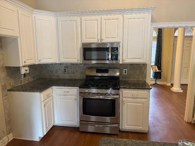 a kitchen with granite countertop white cabinets and appliances