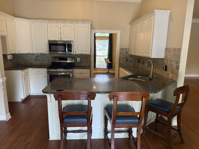 a kitchen with stainless steel appliances granite countertop a table chairs microwave and sink