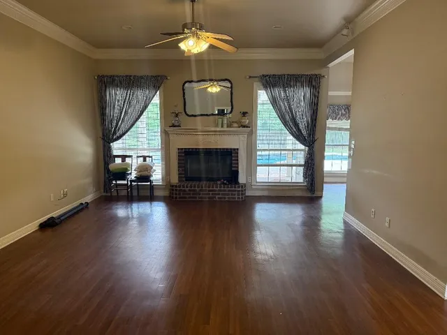 an empty room with wooden floor fireplace and windows
