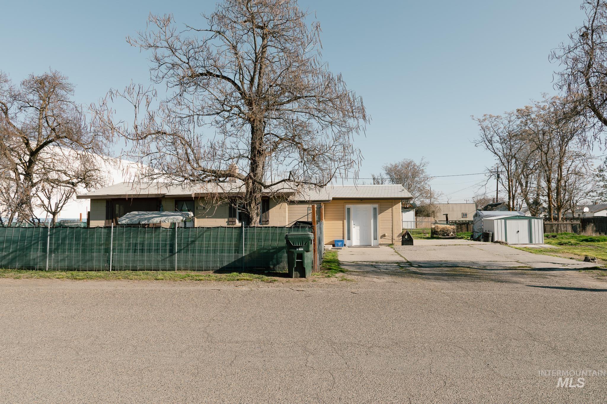 Bungalow-style home with a fenced front yard, a storage unit, and driveway