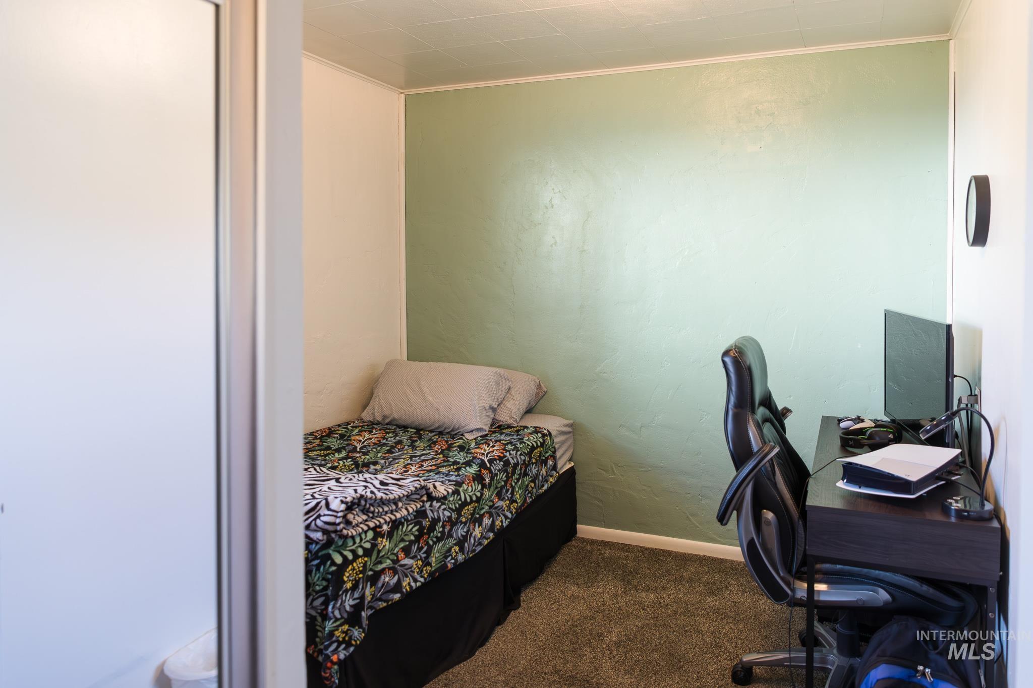 211 Northeast 3rd Avenue Ontario, OR 97914 - Photo 20 of 40 Bedroom with a desk, crown molding, dark carpet, and a textured wall