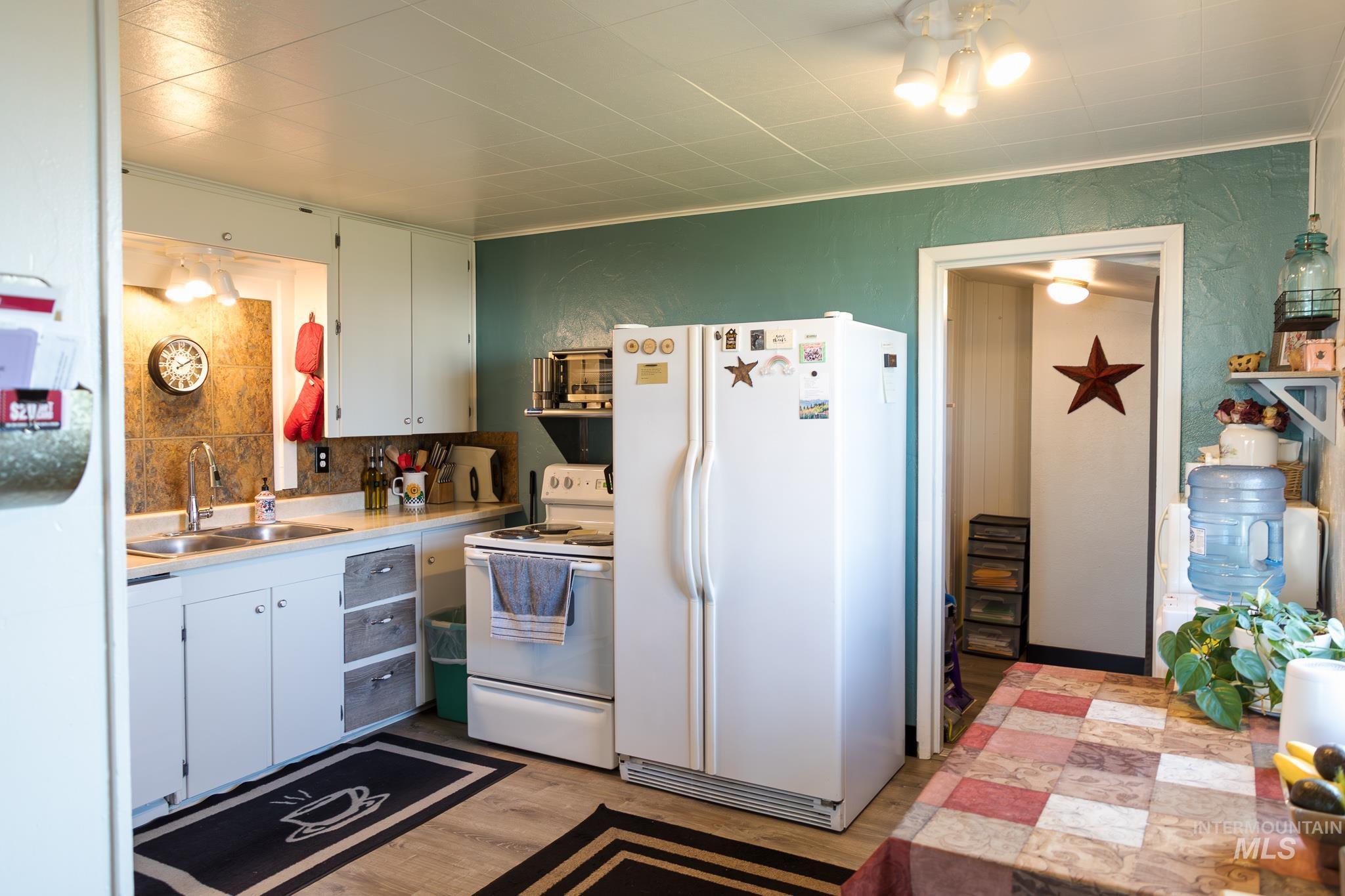 211 Northeast 3rd Avenue Ontario, OR 97914 - Photo 26 of 40 Kitchen featuring white appliances, light countertops, light wood finished floors, ornamental molding, and white cabinets