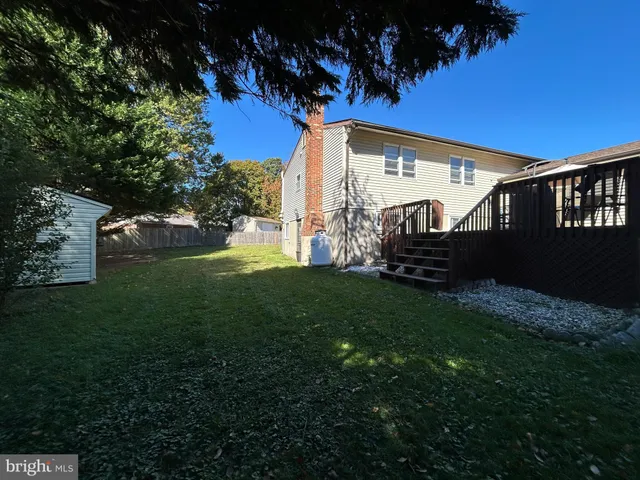 a view of a wooden deck and a big yard with large trees