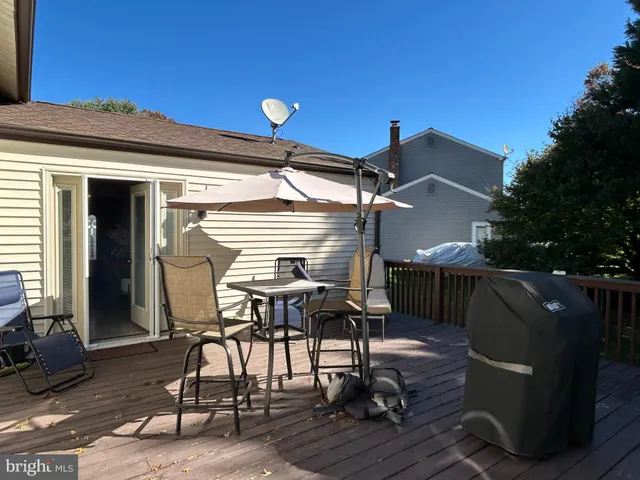 a view of a roof deck with table and chairs under an umbrella with wooden floor