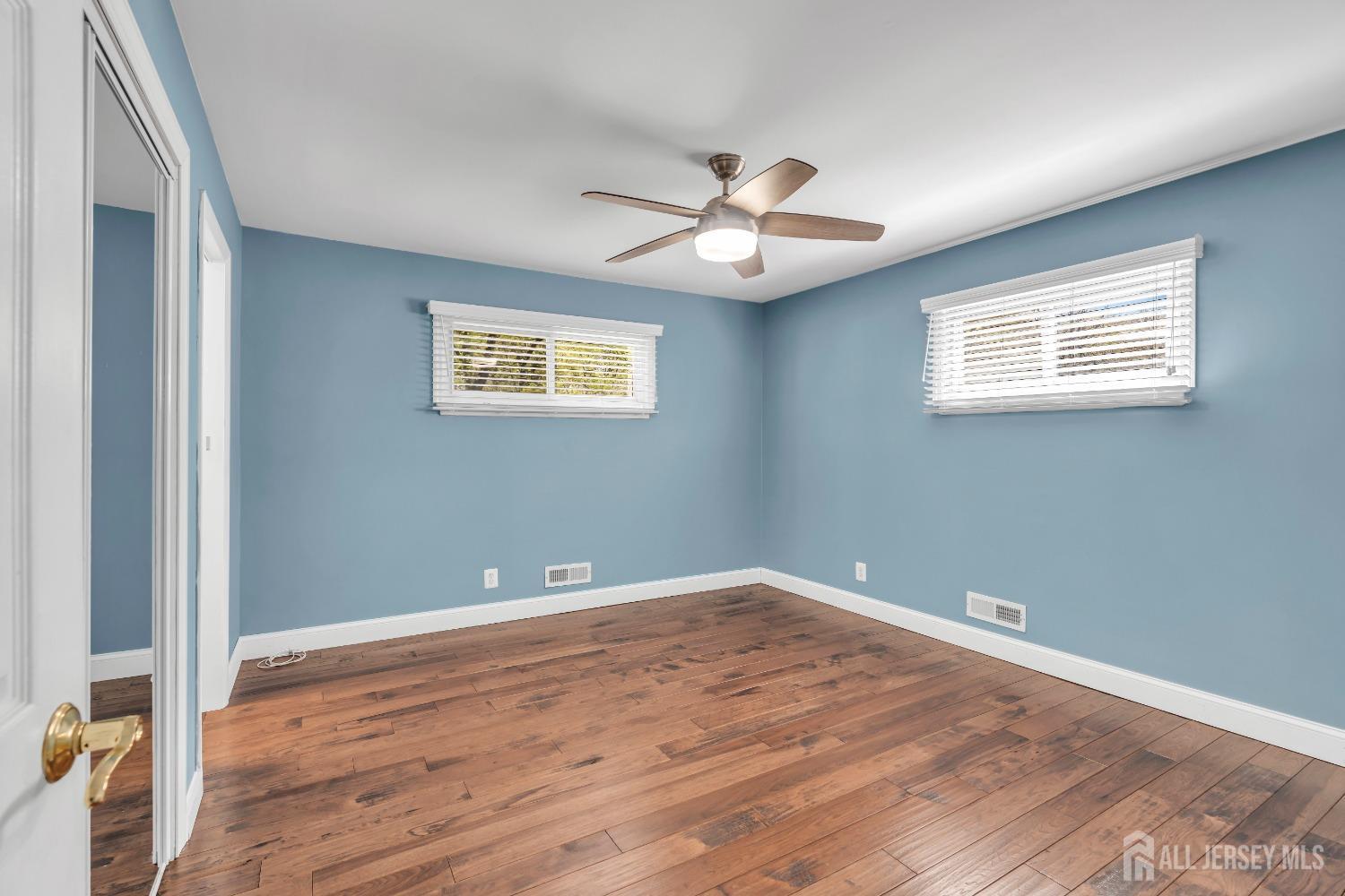27 Brookside Road Edison, NJ 08817 - Photo 15 of 35 an empty room with wooden floor chandelier fan and windows