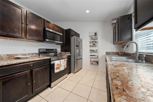 a large kitchen with stainless steel appliances granite countertop a stove a sink and a microwave