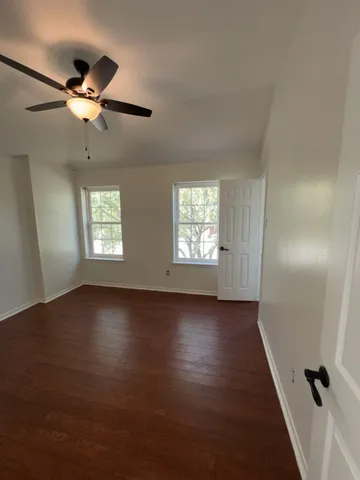 a view of an empty room with a window and wooden floor